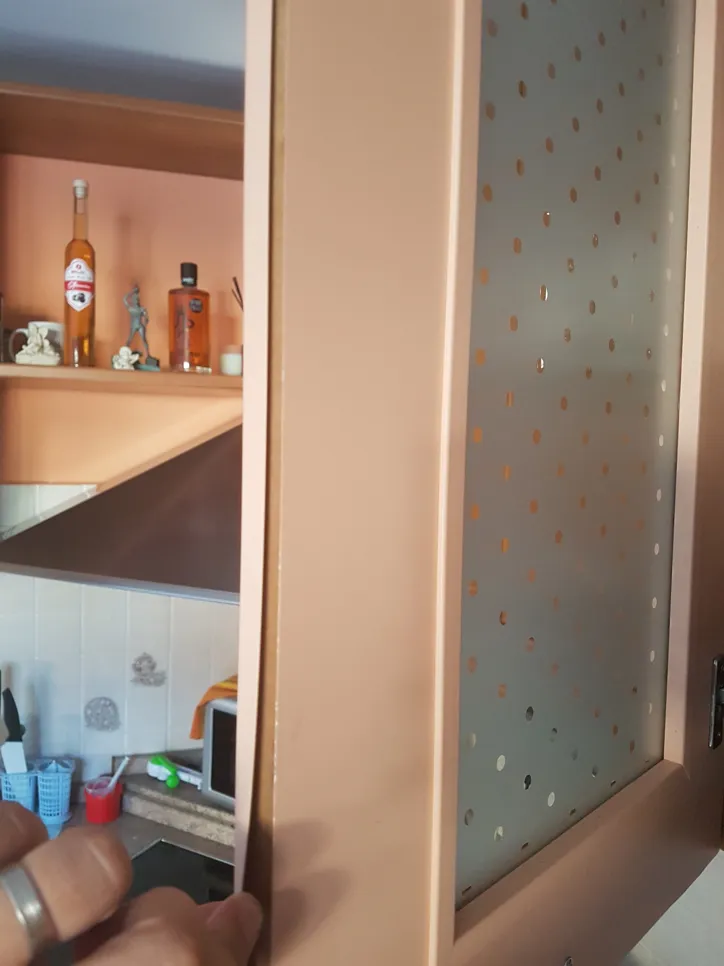 Eine Küchenschranktür erscheint uneben und schief, was auf eine notwendige Anpassung der Scharniere hinweist.