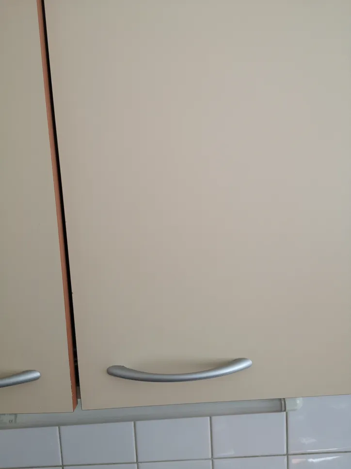 Eine Küchenschranktür scheint schief zu sein, mit sichtbaren Spalten, die auf mögliche Installationsprobleme hinweisen.
